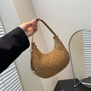 Retro brown crescent shoulder bag with vintage M monogram pattern and gold zipper detail