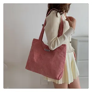Detail of pink corduroy tote bag featuring a Fashion label and soft ribbed texture