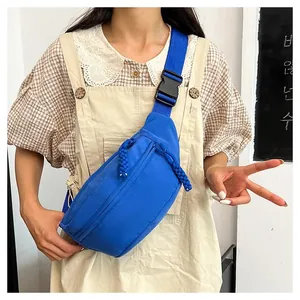 Blue nylon crossbody bag with adjustable strap shown on model in a casual sporty style