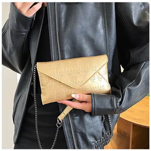 Detailed relief of skull patterns on a champagne gold envelope evening bag with chain