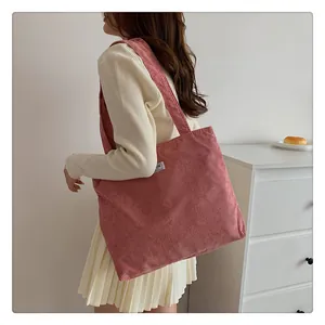 Detail of soft corduroy texture and white woven label on pink shoulder tote bag