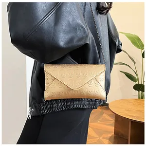 Detail shot of a gold envelope clutch with skull embossing and a sleek chain strap