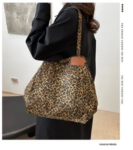 Detail of leopard print tote bag featuring brown leather patch and metallic rivets
