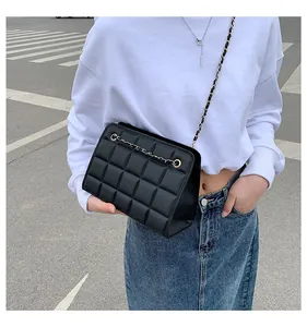 Dettaglio di una borsa a tracolla nera trapuntata con catena d'oro su un outfit