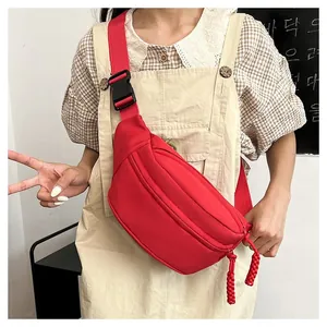 Macro shot of red nylon crossbody bag with black buckle and dual woven zipper pulls