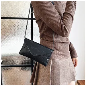 Detail of black envelope clutch with skull embossing and a delicate metal chain strap