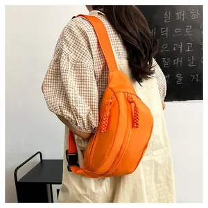 Detail view of orange nylon crossbody bag showing adjustable strap and textured woven pullers