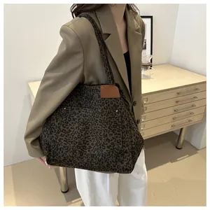 Detail of a leopard print canvas tote bag featuring a leather patch and metal rivet pocket