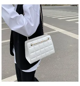 Scatto all'aperto di una borsa a tracolla trapuntata bianca con catena indossata da una modella