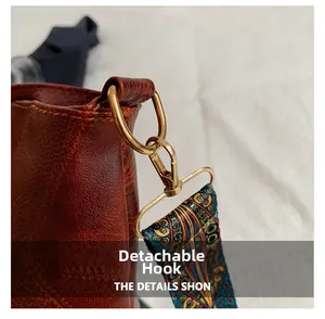 Close-up of detachable gold metal hook and colorful ethnic print strap on a brown leather bag