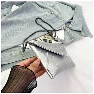 Detail of silver envelope clutch bag with skull embossing and gunmetal chain strap