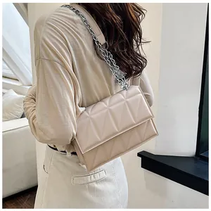 Détail du sac à bandoulière beige matelassé géométrique avec chaîne argentée sur modèle