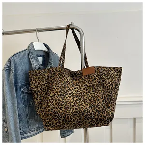 Detail of leopard print tote bag with functional outer pocket and leather patch detail