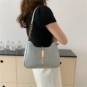 Minimalistische graue Mondsichel-Schultertasche mit goldener Kette am Modell