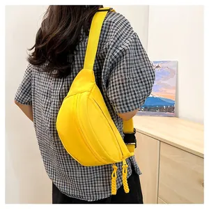 Detail of a bright yellow nylon crossbody bag with dual zippers and adjustable strap