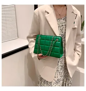 Dettaglio della borsa a catena trapuntata verde indossata da una modella su un blazer