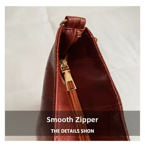 Macro detail of high-quality smooth golden metal zipper on reddish brown leather bag