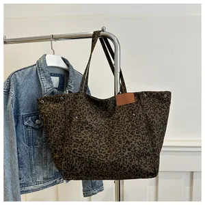 Detail of leopard print canvas tote bag with side silver studs and brown faux leather patch
