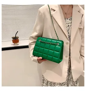 Borsa a tracolla trapuntata verde con catena dorata su modella con blazer color beige
