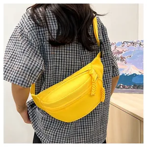 Detail of bright yellow crossbody waist bag with woven zipper pull and adjustable strap