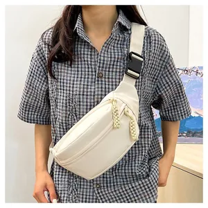 Close-up of minimalist cream crossbody bag featuring woven rope zippers and adjustable strap