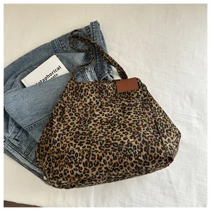 Detail of leopard print canvas tote bag featuring front pocket on denim jacket
