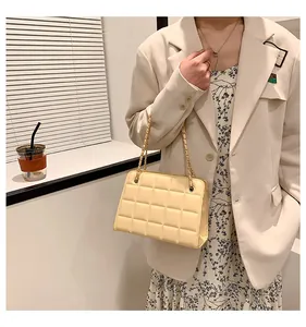 Dettaglio di una borsa a tracolla trapuntata giallo chiaro con catena dorata su modella