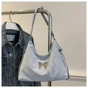Detail van lichtblauwe hobo-tas met gekreukte textuur en zilveren vlinderdecoratie
