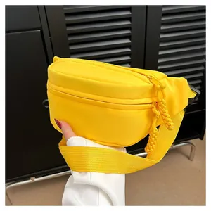 Detail view of the bright yellow nylon waist bag with woven zipper puller and adjustable strap