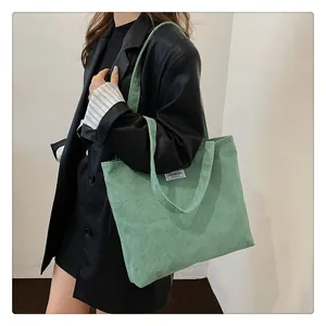 Close-up of the light green corduroy tote bag showing the soft ribbed texture and fashion label