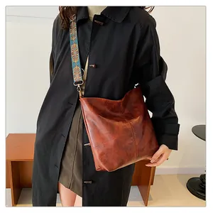 Close-up of brown oiled leather tote with bohemian style wide woven shoulder strap