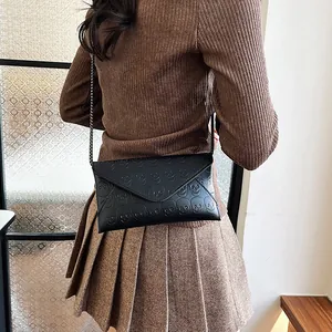 Black envelope crossbody bag with skull embossing and dark grey metal chain strap