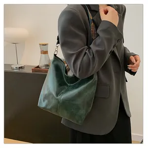Detail of dark green tote bag with oil wax texture and bohemian embroidery strap