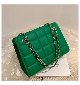 Dettaglio borsa a tracolla verde trapuntata con catena dorata e sfondo floreale chic