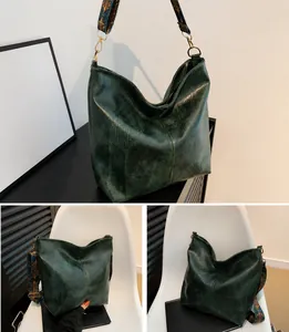 Detailed close-up of dark green hobo bag featuring vintage patterned wide shoulder strap