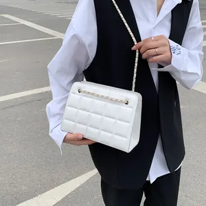 Borsa a tracolla trapuntata bianca con catena dorata indossata da una modella alla moda