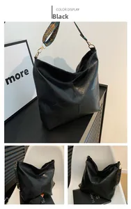 Detail of black tote bag featuring a bohemian patterned wide woven shoulder strap and gold hardware