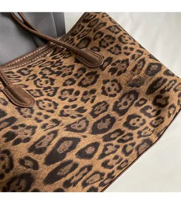 Detailed close-up of leopard print tote bag fabric and brown leather handle stitching