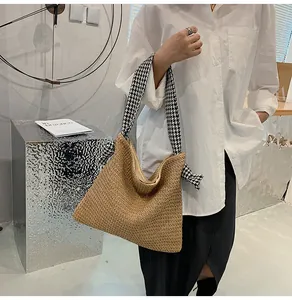 Detail of woven straw tote bag with black and white houndstooth fabric shoulder strap