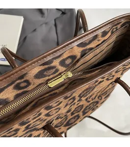 Close-up of leopard print tote bag featuring smooth golden metal zipper and striped lining