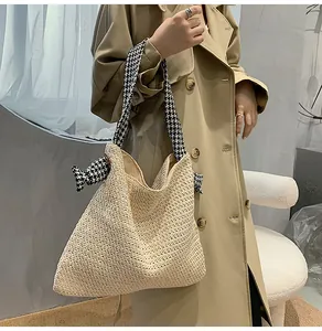 Detail of hand-woven straw tote bag with black and white houndstooth ribbon strap