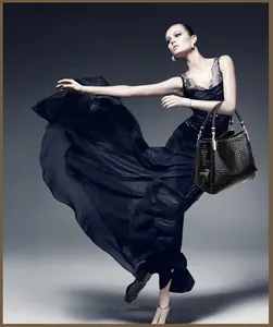 Dettaglio di un'elegante borsa nera con motivo a coccodrillo portata da una modella