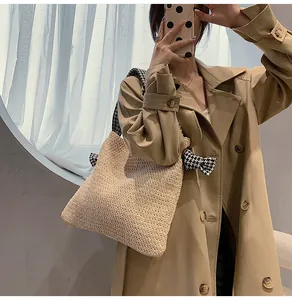 Detail of straw tote bag with houndstooth bow ribbon and woven texture on model