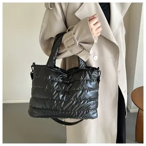 Detail of black quilted puffer tote bag shown on model with crossbody strap