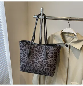 Detail of vintage leopard print tote bag hanging on a rack with soft shadow lighting