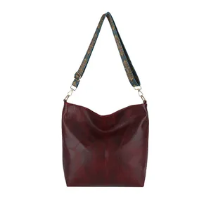 Burgundy faux leather hobo bag with patterned woven shoulder strap and golden buckle