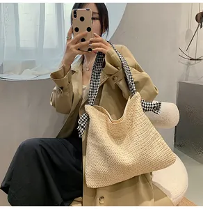 Close-up of straw woven tote bag featuring a black and white houndstooth fabric strap