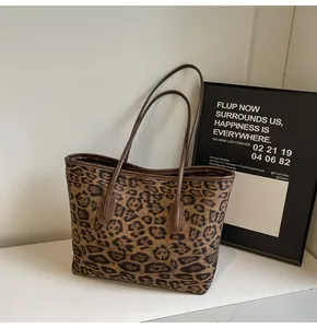Close-up of leopard print tote bag with brown leather handles on marble countertop