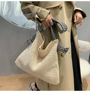 Detail of straw tote bag with houndstooth fabric handles and bow decoration
