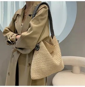 Detail of beige straw woven tote bag featuring stylish houndstooth pattern strap